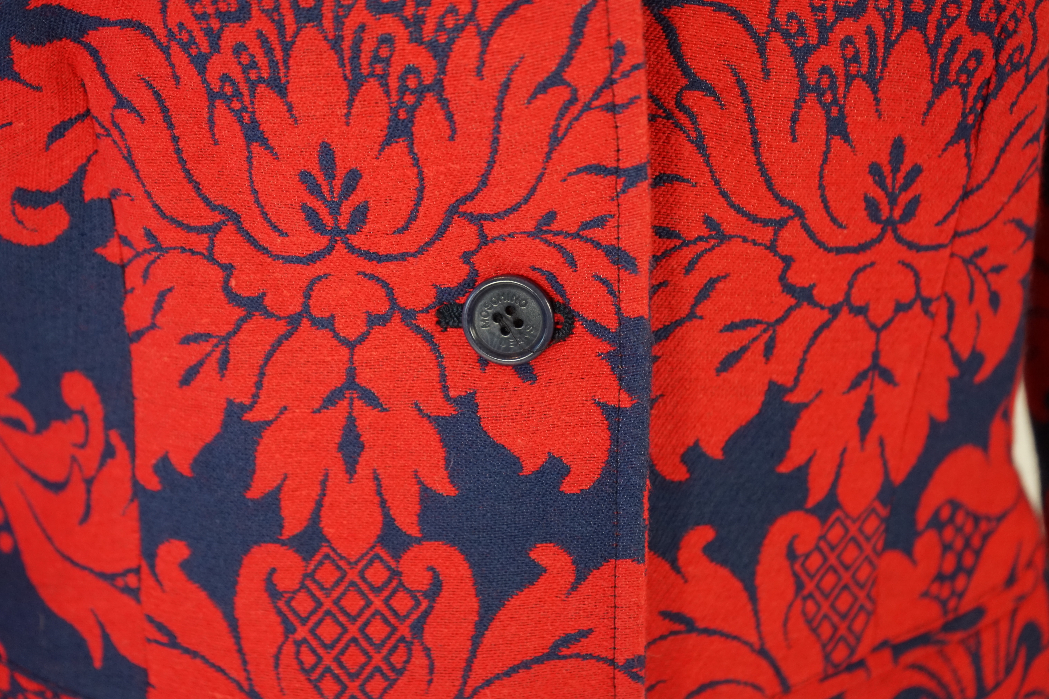 A Moschino lady's long blue and red jacket, a cream cotton embellished blazer and a cotton pair of floral trousers, blue and red jacket size 14, cream blazer size 12, trousers size: 10